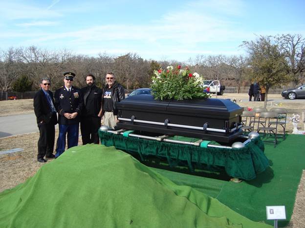 A group of people standing around a coffin

Description automatically generated