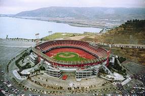 A stadium with a green field and a lake

Description automatically generated