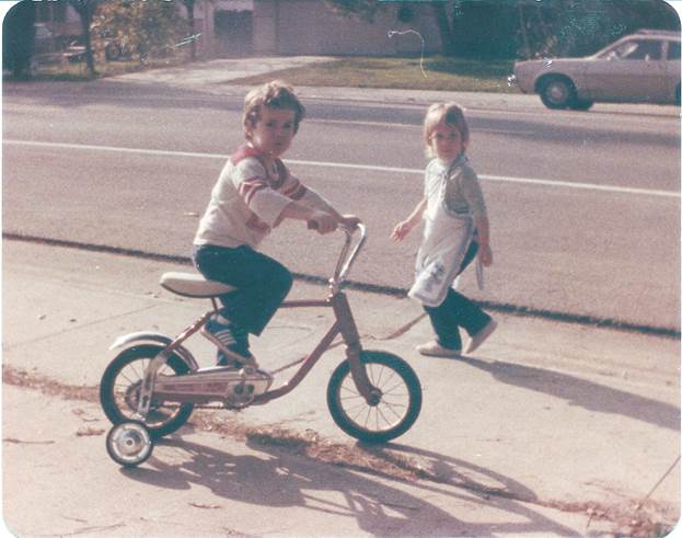 A child and child riding a bicycle

Description automatically generated