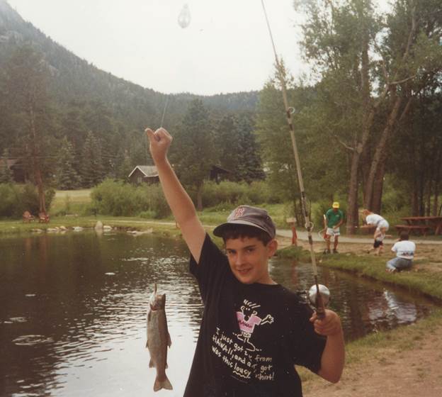 A child holding a fish and fishing rod

Description automatically generated