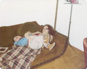 A person lying on a couch with a baby

Description automatically generated