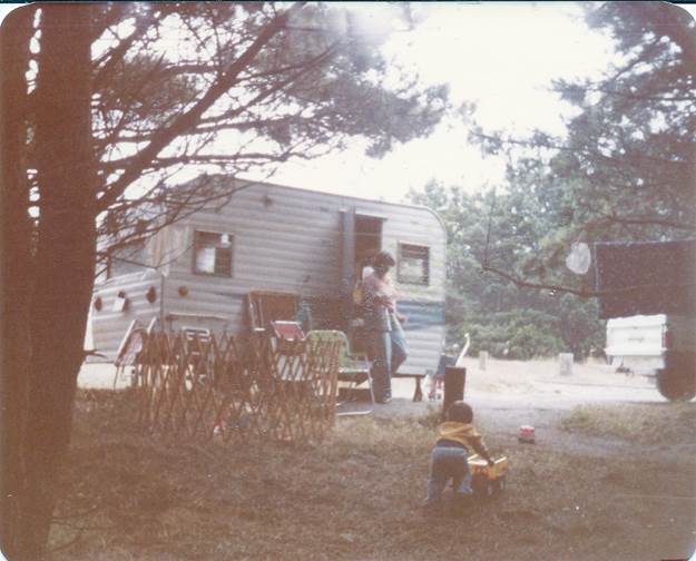 A person playing guitar in front of a trailer

Description automatically generated