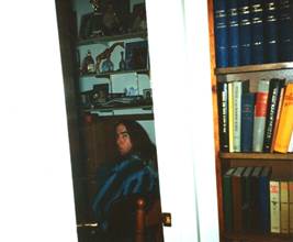 A person sitting in a chair in front of a bookcase

Description automatically generated