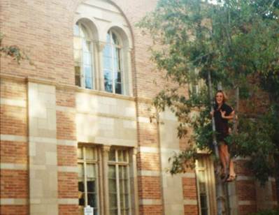 A person on a tree in front of a building

Description automatically generated