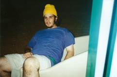 A person in a blue shirt and yellow hat sitting on a bathtub

Description automatically generated